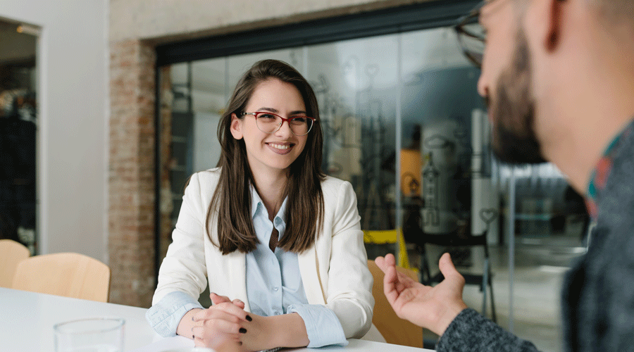 Femme avec une blouse, une veste et des lunettes à un entretien d'embauche